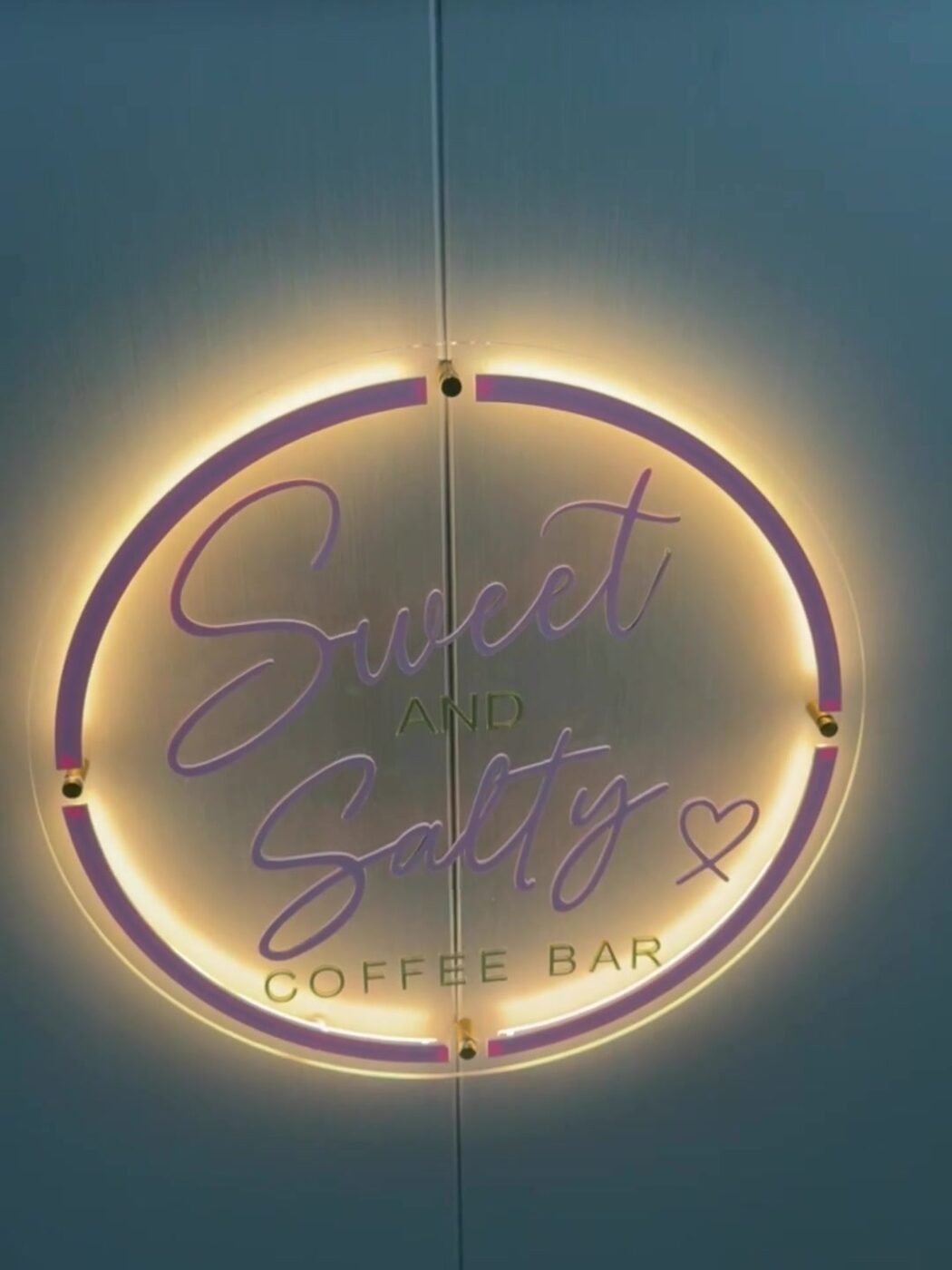 The lit S&S Coffee Bar logo on the front of the bar